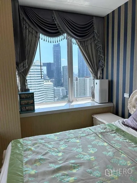 Condominium for sale in Huai Khwang, Bangkok - Bedroom corner with large window, elegant drapes and skyline outlook.