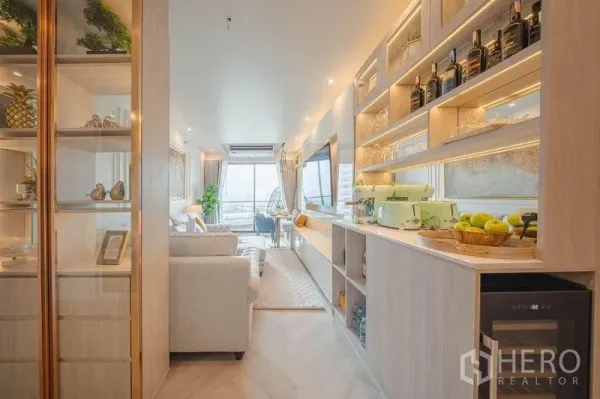 คอนโด ให้เช่า - ห้องนั่งเล่นยาว ชั้นวางของ มุมมินิบาร์ โซฟา และระเบียง โทนไม้สว่าง