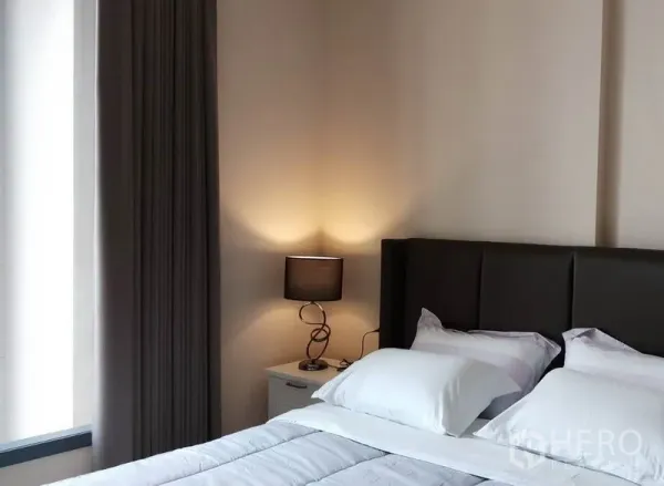 公寓 出租在Khlong Toei, Bangkok - 温馨卧室，软包床头与床头灯，旁有大窗与遮光窗帘