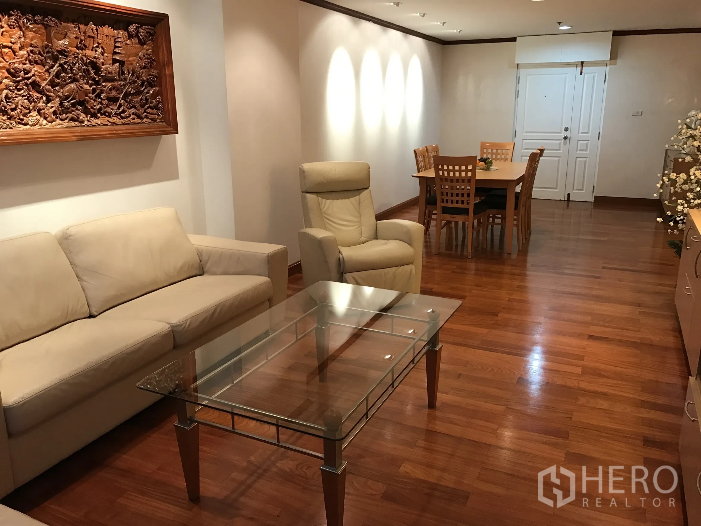 公寓 出租在Khlong Toei, Bangkok - 客厅朝餐桌视角，木地板与木雕墙饰。