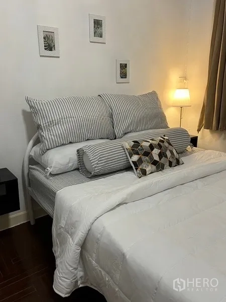 Home Office for rent in Suan Luang, Bangkok - Cozy bedroom with striped bedding, soft lighting and wall art.