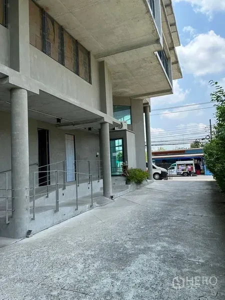 Home Office for rent or sale in Prawet, Bangkok - Ground-level driveway and columns with glass corner windows at the front of the building.