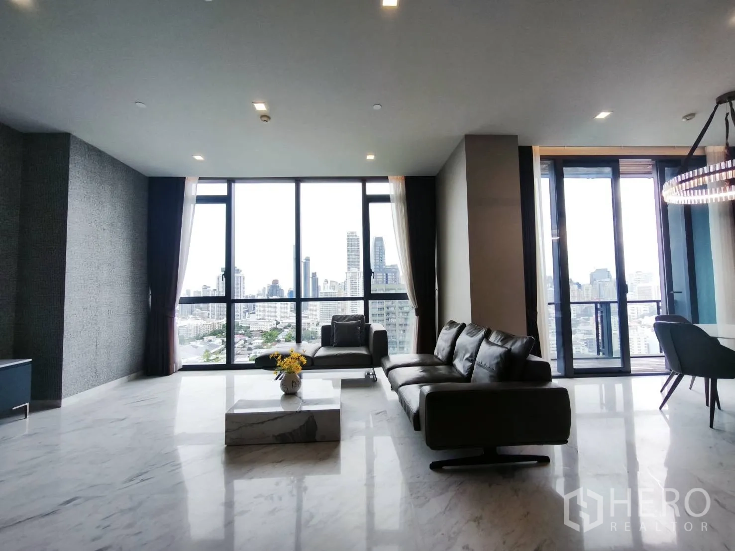 Condominium for rent in Watthana, Bangkok - Living room with large windows, marble floor, and leather sofas.