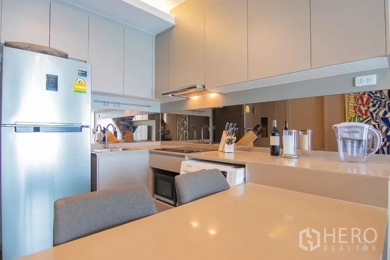 Condominium for rent in Phra Khanong, Bangkok - Fully fitted L-shaped kitchen with cabinets, cooktop and breakfast counter.