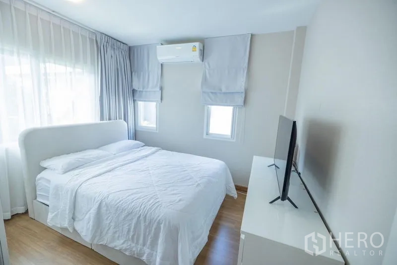 Detached House for sale in Prawet, Bangkok - Bright bedroom with white bed, soft curtains, air conditioner and TV console.