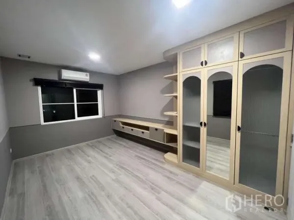 Detached House for rent in Prawet, Bangkok - Spacious bedroom with custom wardrobe, TV console and grey flooring.
