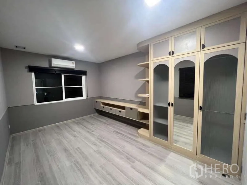 Detached House for rent in Prawet, Bangkok - Spacious bedroom with custom wardrobe, TV console and grey flooring.