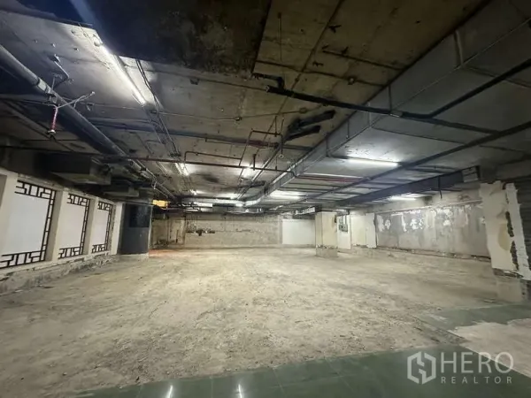 零售空间 出租 - 宽敞店铺，裸露混凝土墙面与天花管线，照明明亮。