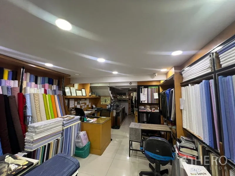 อาคารพาณิชย์ ให้เช่าหรือขายในWatthana, Bangkok - พื้นที่ค้าปลีกชั้นล่างจัดแสดงผ้า เคาน์เตอร์ และไฟดาวน์ไลท์สว่าง.