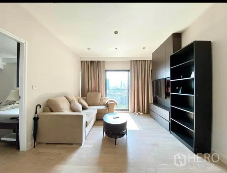 คอนโด ให้เช่าในKhlong Toei, Bangkok - ห้องนั่งเล่นอบอุ่น โซฟาสองตัว โต๊ะกลาง ชุดผนังทีวี และทางเข้าห้องนอน