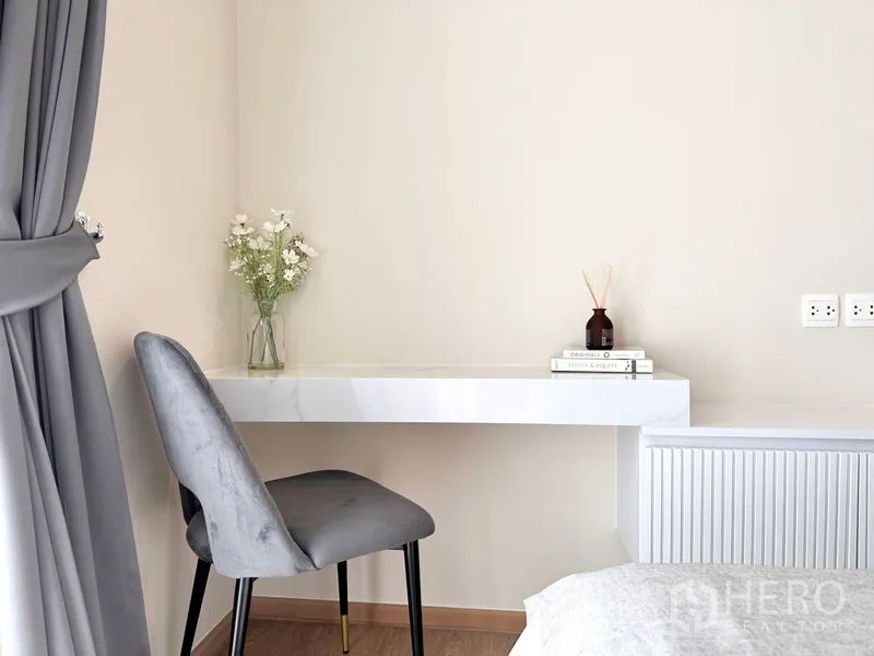 公寓 出租在Watthana, Bangkok - 温馨工作角，悬空白色书桌、灰色椅与装饰花。