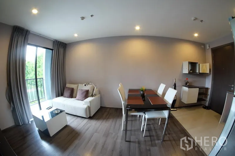 公寓 出租在Watthana, Bangkok - 现代感客餐厅与阳台相连，旁为紧凑实用的开放式厨房。