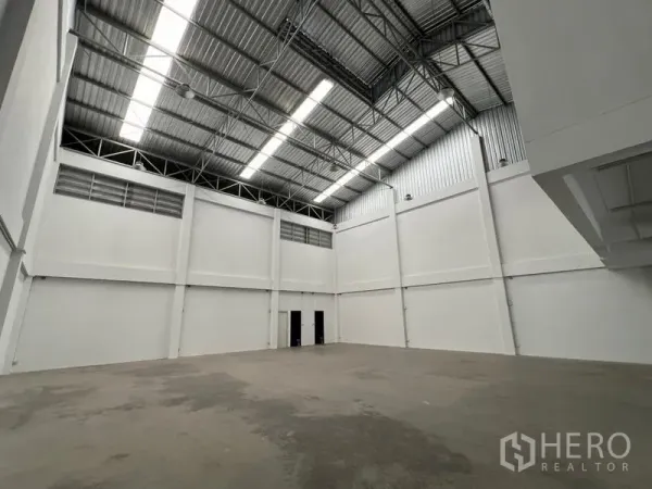 货栈 出租在Phra Samut Chedi, Samut Prakan - 宽敞仓库内景，高钢结构屋顶与天窗，墙面洁白。