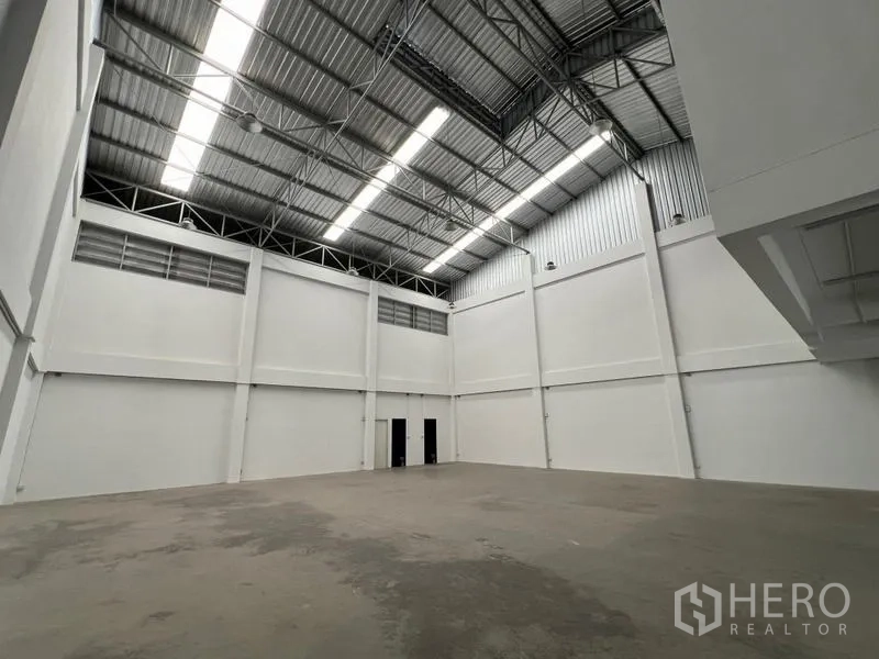 货栈 出租在Phra Samut Chedi, Samut Prakan - 宽敞仓库内景，高钢结构屋顶与天窗，墙面洁白。