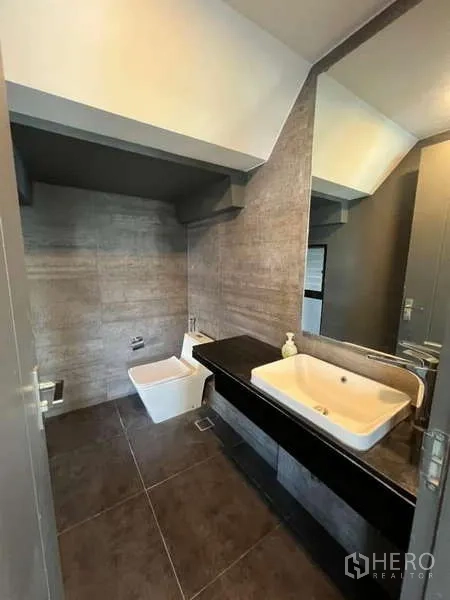 Detached House for rent or sale in Bang Phli, Samut Prakan - Powder room with wall‑hung toilet, vanity and textured grey tiles.