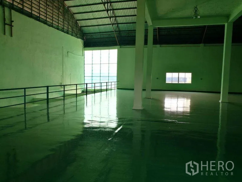 Factory for rent in Mueang Samut Sakhon, Samut Sakhon - Open mezzanine factory floor under a high arched roof with skylight panel and safety railing.