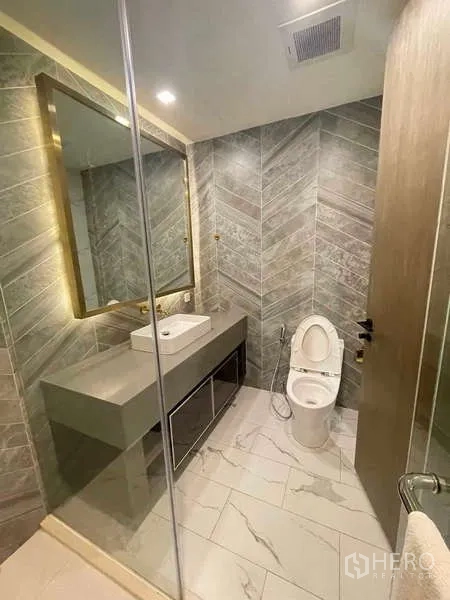 คอนโด ให้เช่าหรือขายในKhlong Toei, Bangkok - ห้องน้ำพร้อมกระจกบานใหญ่ เคาน์เตอร์อ่างล้างหน้า โถสุขภัณฑ์ และผนังลายก้างปลา