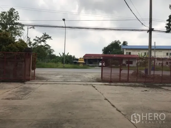 货栈 出租在Mueang Nakhon Pathom, Nakhon Pathom - 仓库红色大门通向马路，带路灯与周边建筑