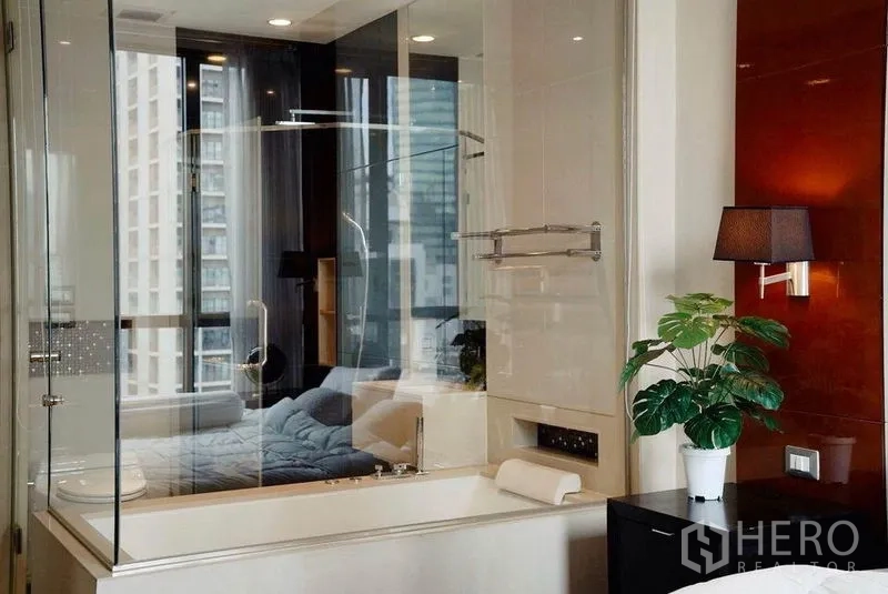 คอนโด ให้เช่าในKhlong Toei, Bangkok - อ่างอาบน้ำข้างผนังกระจก โคมไฟและกระถางต้นไม้ วิวตึกสูง