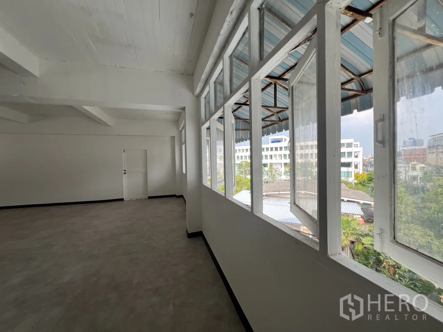 Office Space for rent in Watthana, Bangkok - Internal corridor with awning windows overlooking neighborhood greenery and low-rise roofs.