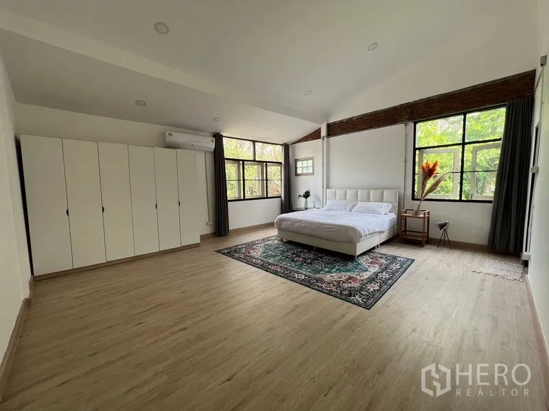 Townhouse for rent in Ratchathewi, Bangkok - Spacious master bedroom with large windows, white wardrobe and wood-look flooring.