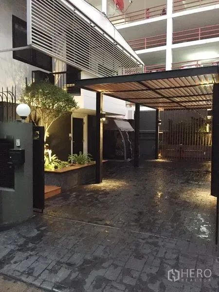 บ้าน ให้เช่าในWatthana, Bangkok - ทางเข้าและโรงจอดรถมีหลังคา พร้อมสวนตกแต่งและไฟส่องสว่าง บรรยากาศเอกมัย กรุงเทพฯ