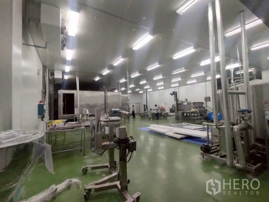 Factory for rent or sale in Mueang Nakhon Pathom, Nakhon Pathom - Large production hall with stainless machinery, piping, and green epoxy flooring.