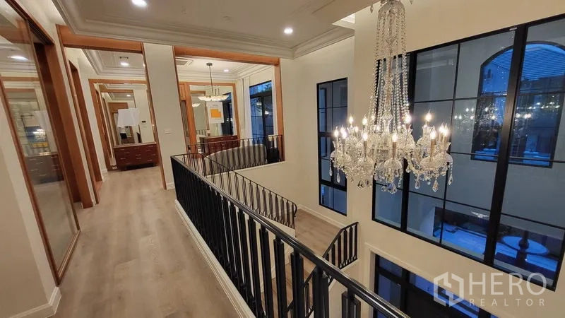 Detached House for rent or sale in Saphan Sung, Bangkok - Upstairs landing with crystal chandelier overlooking large grid windows and staircase.
