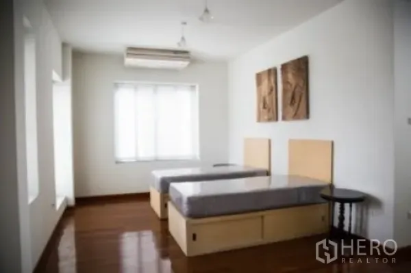 บ้าน ให้เช่าในKhlong Toei, Bangkok - ห้องนอนสว่างด้วยเตียงคู่ พื้นไม้ และหน้าต่างบานกว้างพร้อมม่านโปร่ง