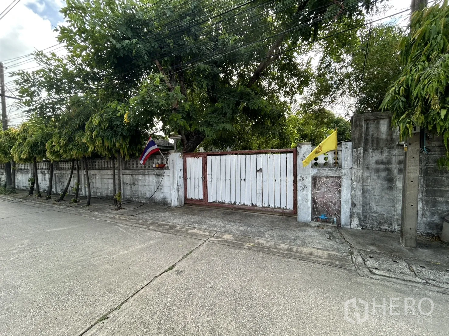 独栋房屋 for sale in Phra Khanong, Bangkok - 街景视角，可见围墙与木制滑动大门。