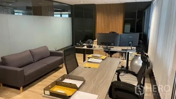 สำนักงาน ให้เช่าในKhlong Toei, Bangkok - พื้นที่ทำงานส่วนตัวพร้อมโซฟาสีเทา โต๊ะทำงาน และผนังกั้นกระจกฝ้า