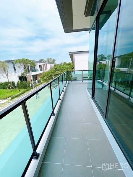 Detached House for sale in Don Mueang, Bangkok - Long glass-railed balcony overlooking landscaped street and neighboring homes.