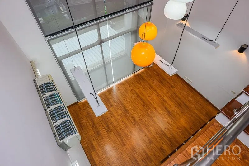 联排别墅 出租在Watthana, Bangkok - 从夹层俯视双层客厅，木地板与吊灯