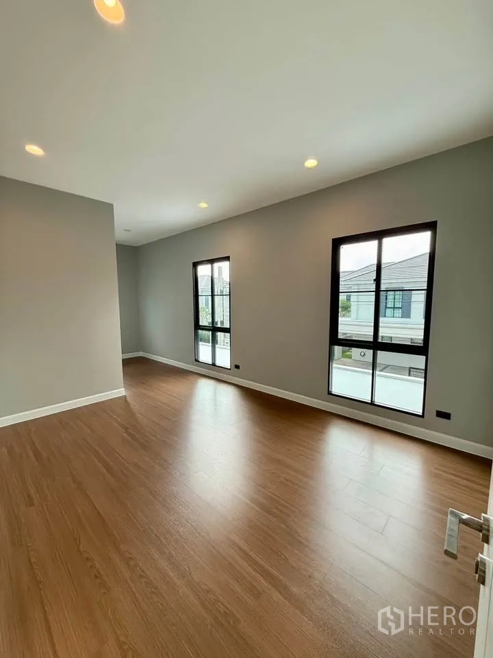 Detached House for rent in Don Mueang, Bangkok - Spacious empty room with wood floors and large windows.