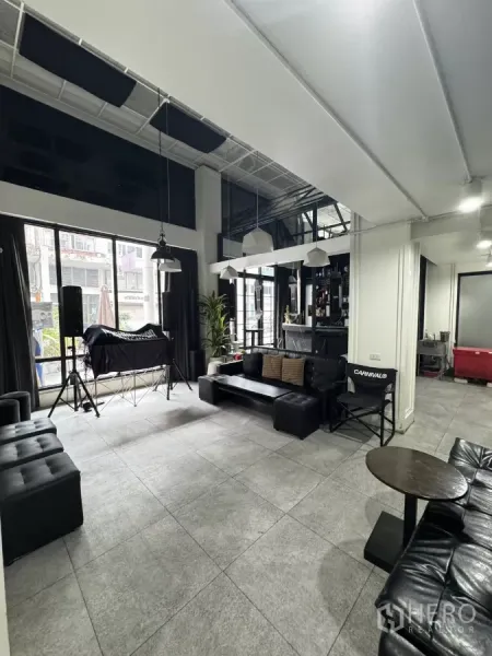 อาคารพาณิชย์ ให้เช่าในKhlong Toei, Bangkok - โซนรับรองกว้าง กระจกสูงจรดเพดาน โซฟาหนังสีดำ และเคาน์เตอร์บาร์ขนาดกะทัดรัด