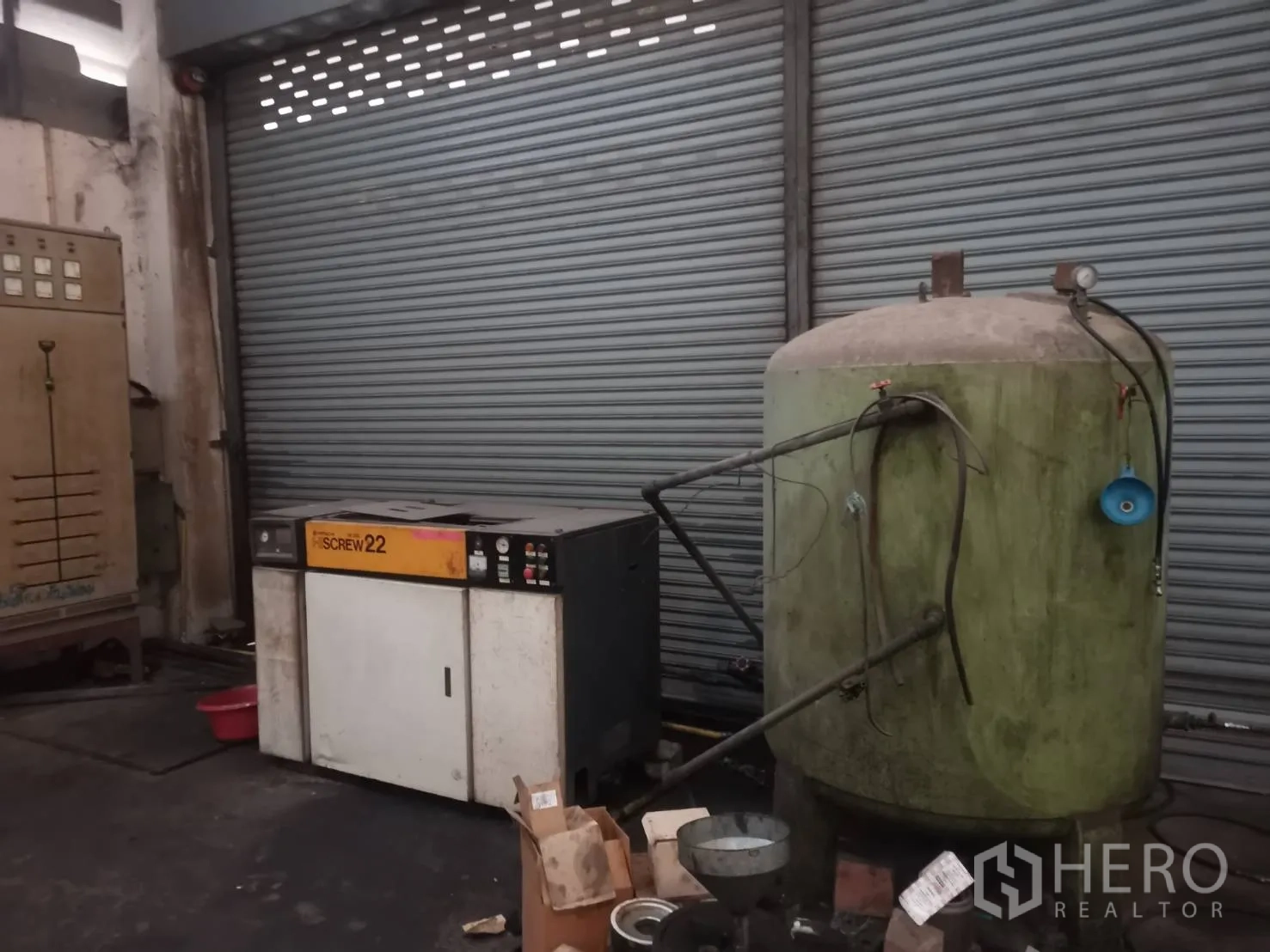 工厂 出租或出售在Bang Khun Thian, Bangkok - 空压机与储气罐，旁边为卷帘门。