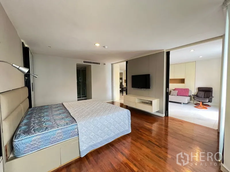 คอนโด ให้เช่าหรือขายในKhlong Toei, Bangkok - ห้องนอนกว้างพื้นไม้พร้อมเตียงและทีวี มองไปยังโซนนั่งเล่น