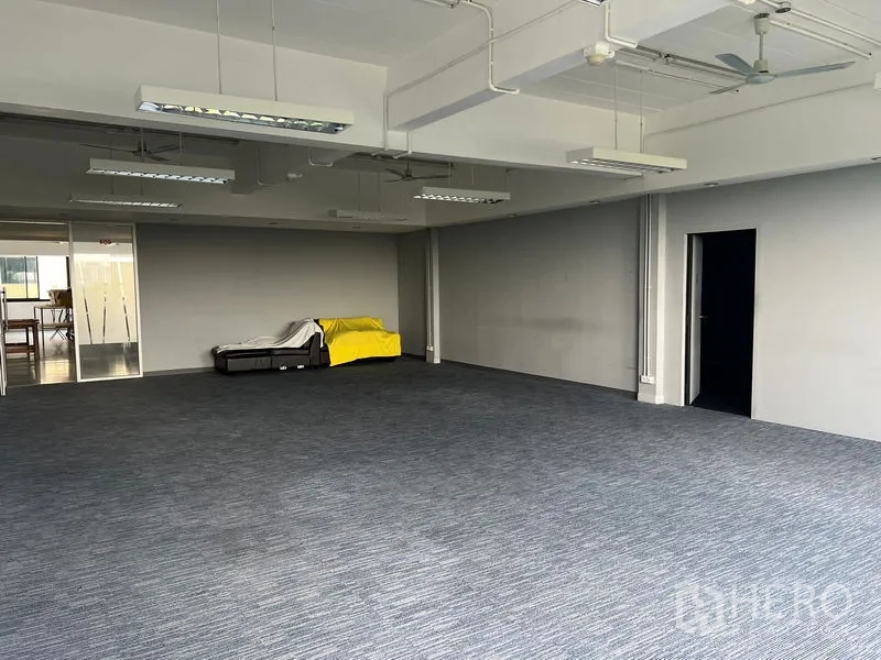 Office Space for rent in Mueang Samut Prakan, Samut Prakan - Large carpeted open office with grey walls and suspended lighting.