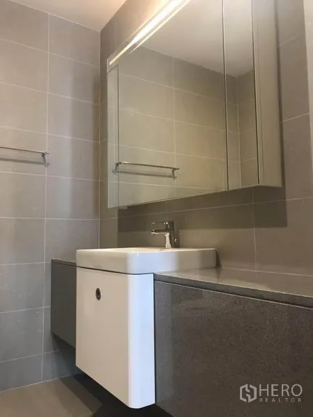 Condominium for rent or sale in Pathum Wan, Bangkok - Bathroom vanity with square sink, mirrored cabinet and stone countertop.