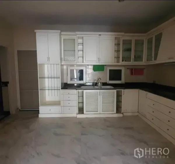 ทาวน์เฮาส์ ให้เช่าในHuai Khwang, Bangkok - ครัวตัวแอลโทนขาว ตู้กระจกบานเลื่อน อ่างล้างจานคู่ และท็อปหินสีดำ