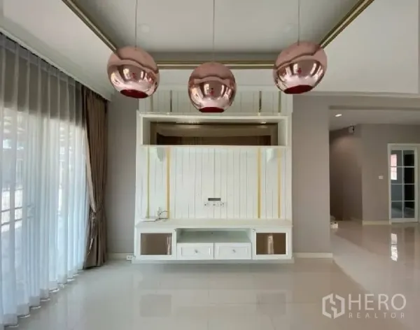 บ้าน ให้เช่าในSuan Luang, Bangkok - มุมผนังทีวีบิลต์อินสีขาวพร้อมโคมแขวนทรงกลมสีโรสโกลด์สามดวง