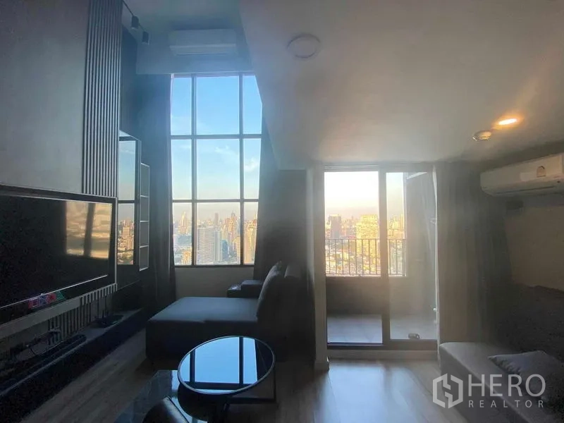 公寓 出租或出售在Sathon, Bangkok - 客厅落地窗与阳台，眺望曼谷城市景观。