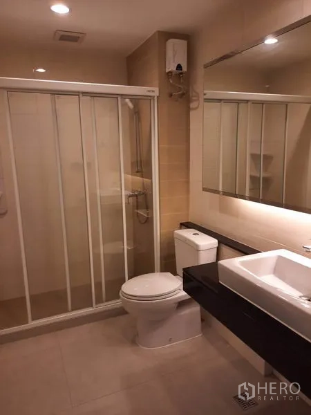 公寓 出租在Watthana, Bangkok - 现代卫浴，玻璃淋浴间、大镜面、方形洗手盆与坐便器。