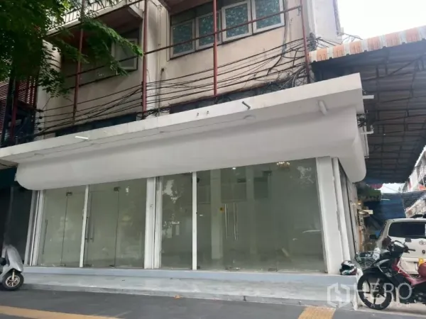 零售空间 出租在Khlong Toei, Bangkok - 地面层店面外立面，整面玻璃橱窗与白色雨棚，临街位置。