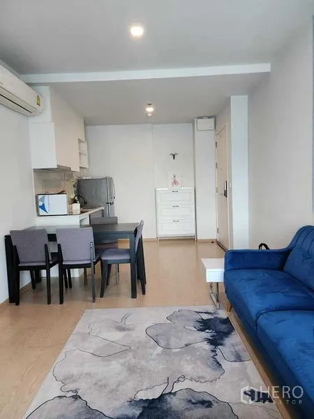 公寓 出租 - 开放式客餐厅，蓝色沙发、地毯与紧凑厨房。