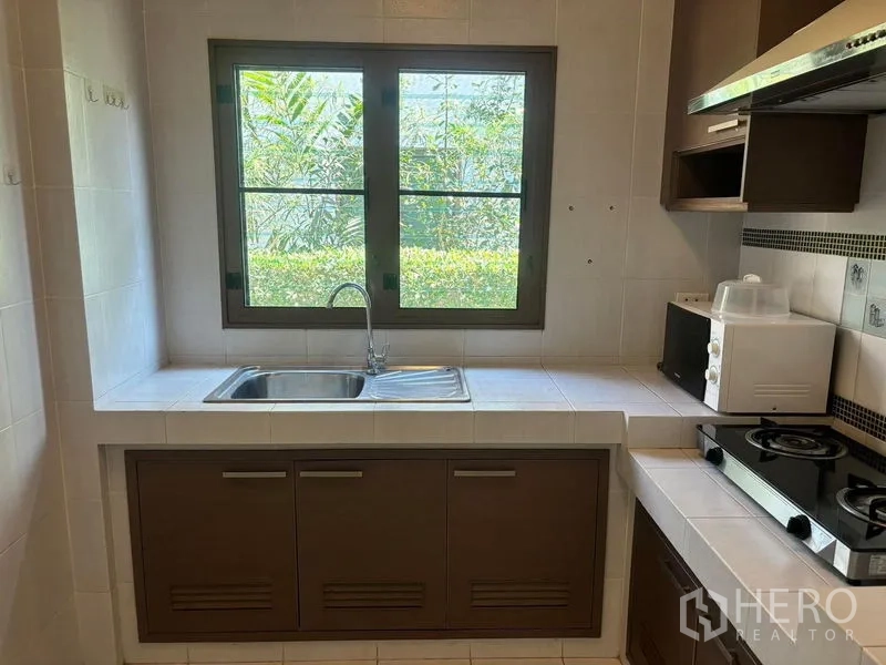 Detached House for rent in Bang Phli, Samut Prakan - Kitchen sink under a wide window overlooking green hedges.