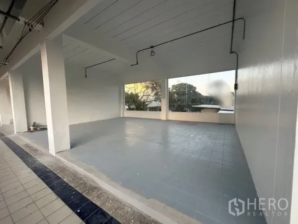 零售空间 出租 - 从有顶走廊望向店铺的宽阔门面，干净的瓷砖地与落地窗。