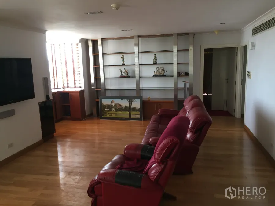 公寓 出租在Khlong Toei, Bangkok - 宽敞客厅，木地板、红色皮沙发、内置搁架与壁挂电视