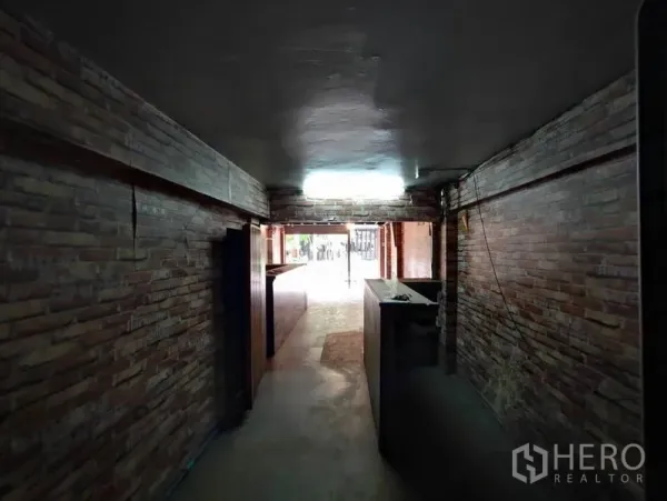 Shophouse for rent in Khlong Toei, Bangkok - Long hallway-style retail area with brick walls leading to the street entrance.