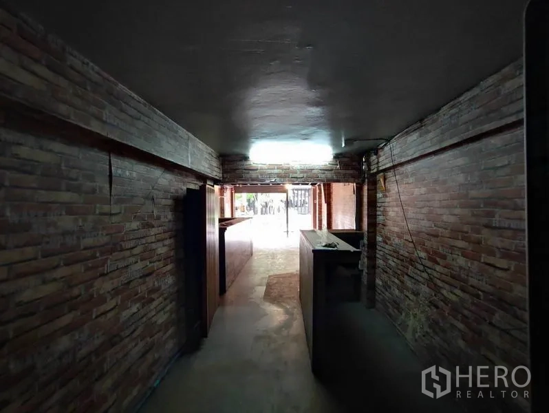 Shophouse for rent in Khlong Toei, Bangkok - Long hallway-style retail area with brick walls leading to the street entrance.